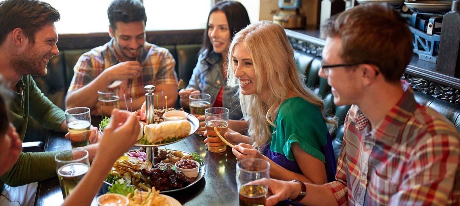 Friends sharing platters and pints around a pub table