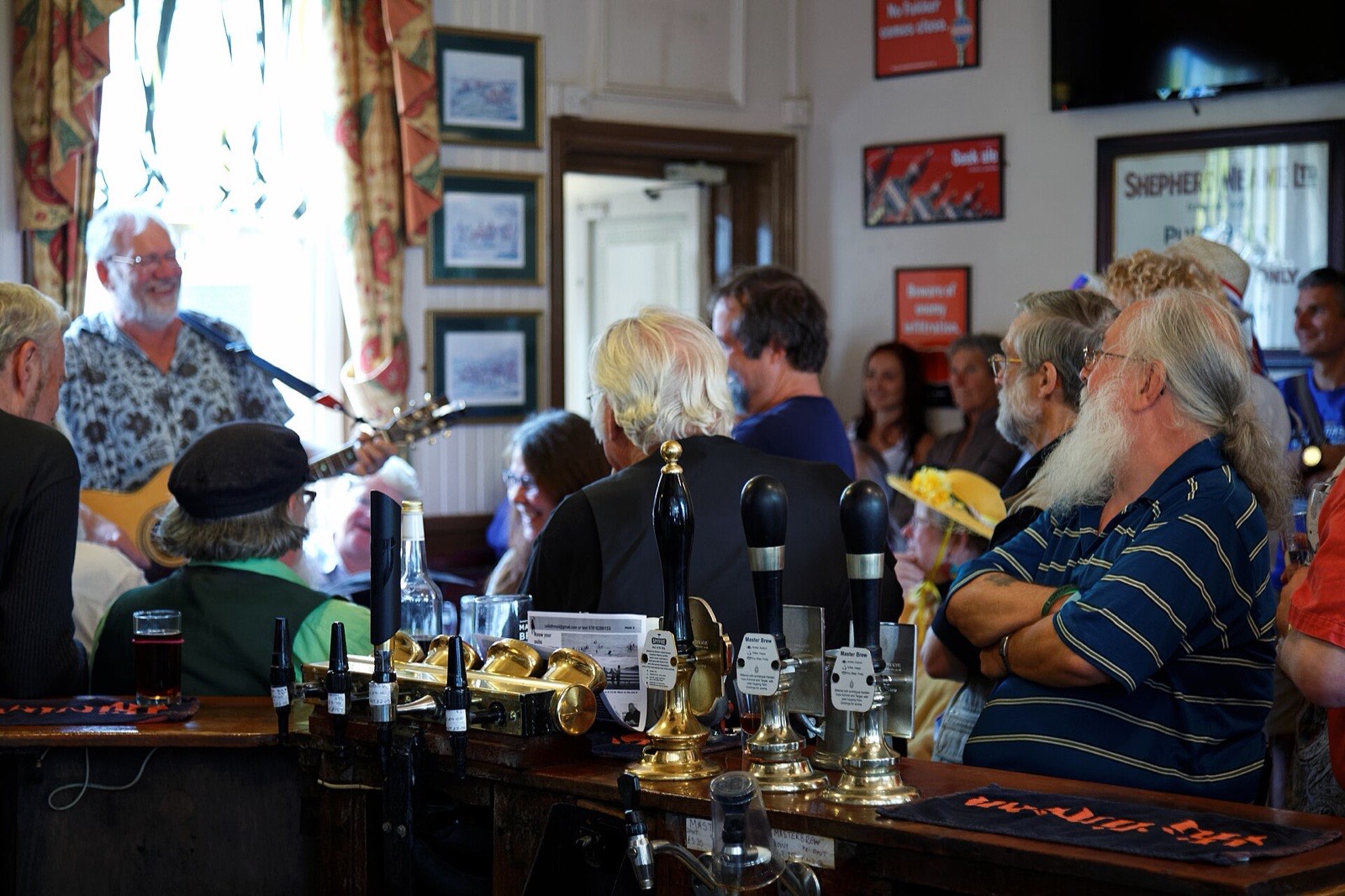 Musicians playing guitars to a full pub floor beside the bar