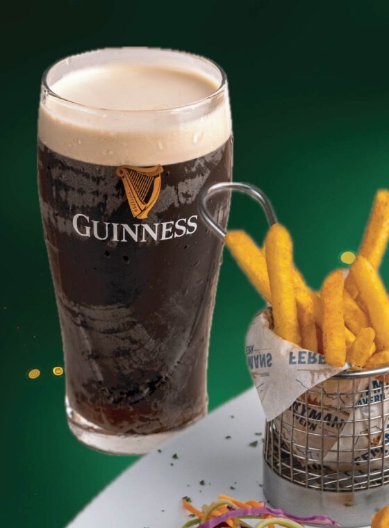 A pint of Guinness draught settling beside a basket of chips